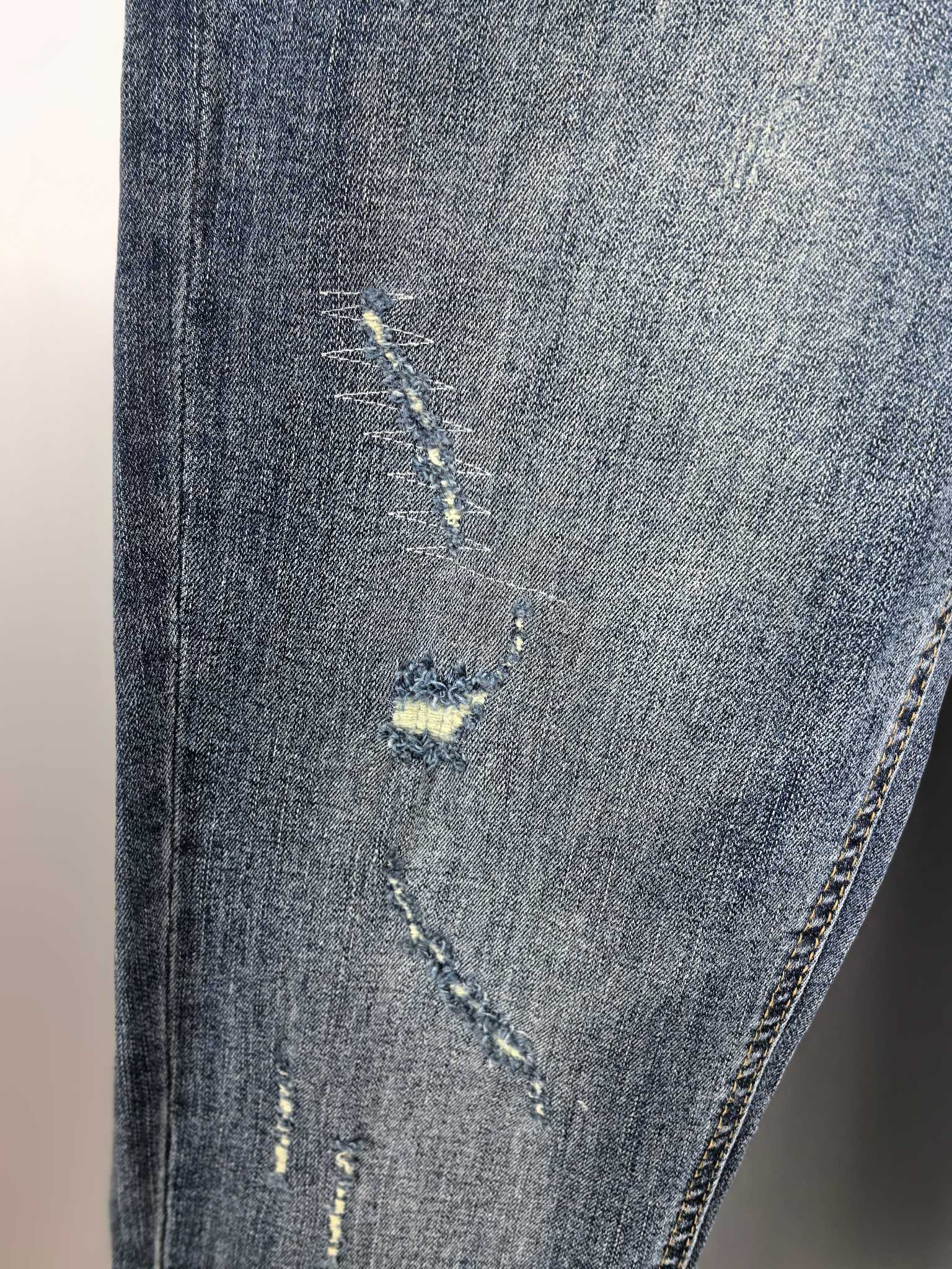Denim pants leg with distressed yellow patch and visible hand-stitching