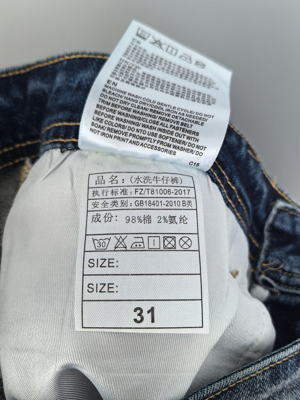 Denim pants care label with size 31 and washing instructions