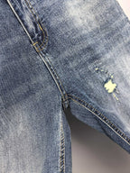 Denim pants side seam with distressed opening and small yellow repair patch