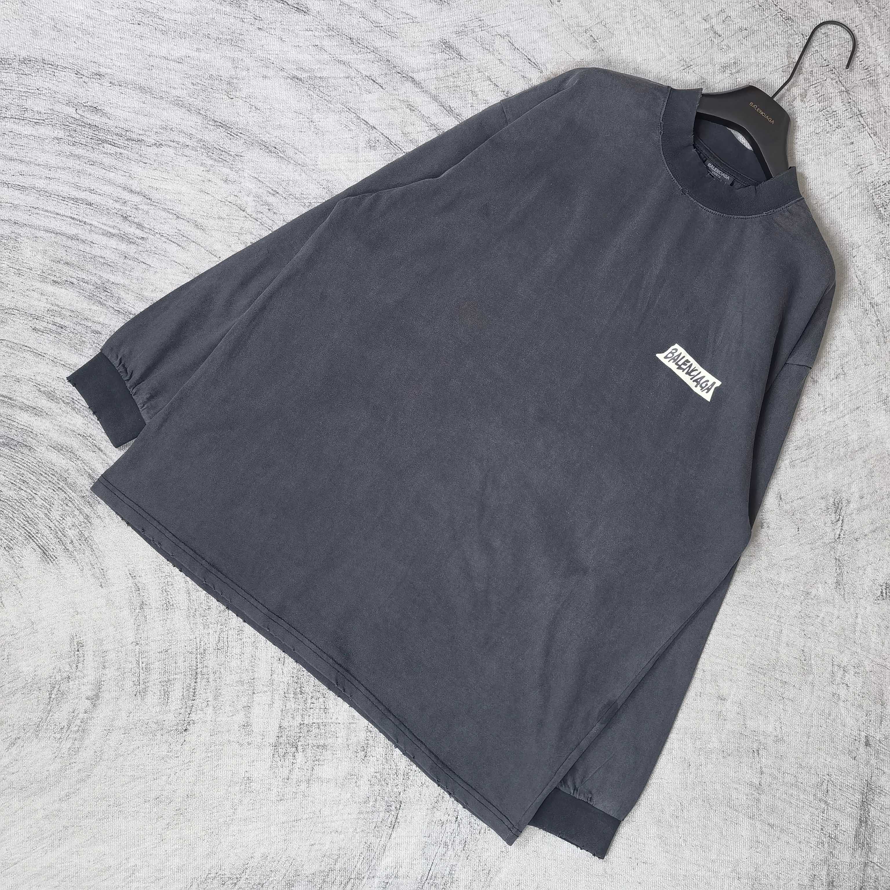 Balenciaga long-sleeve top laid flat, dark charcoal gray, small chest logo patch