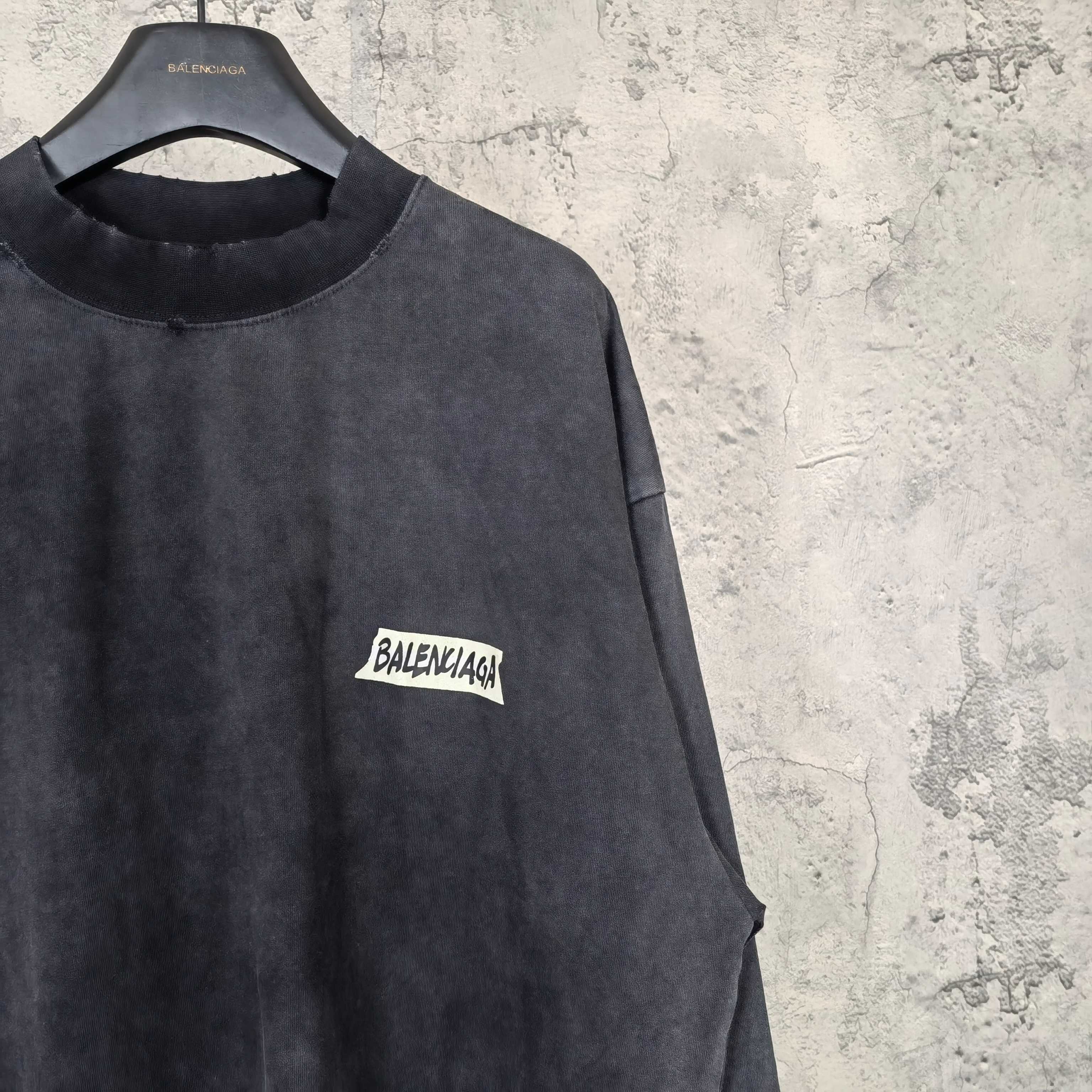 Balenciaga long-sleeve top side view, dark charcoal gray, small BALENCIAGA logo patch