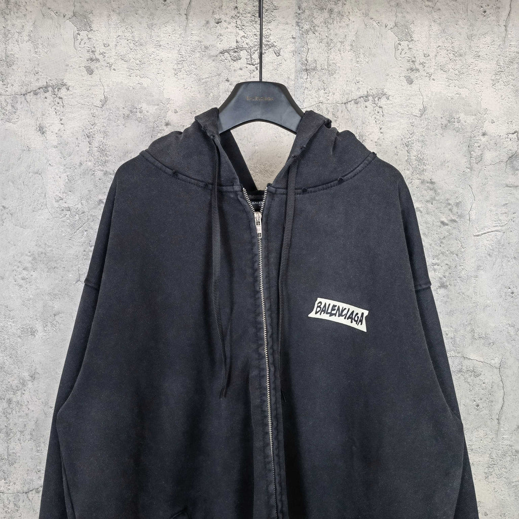 Black zip-up hoodie with hood, front zipper, and chest logo patch