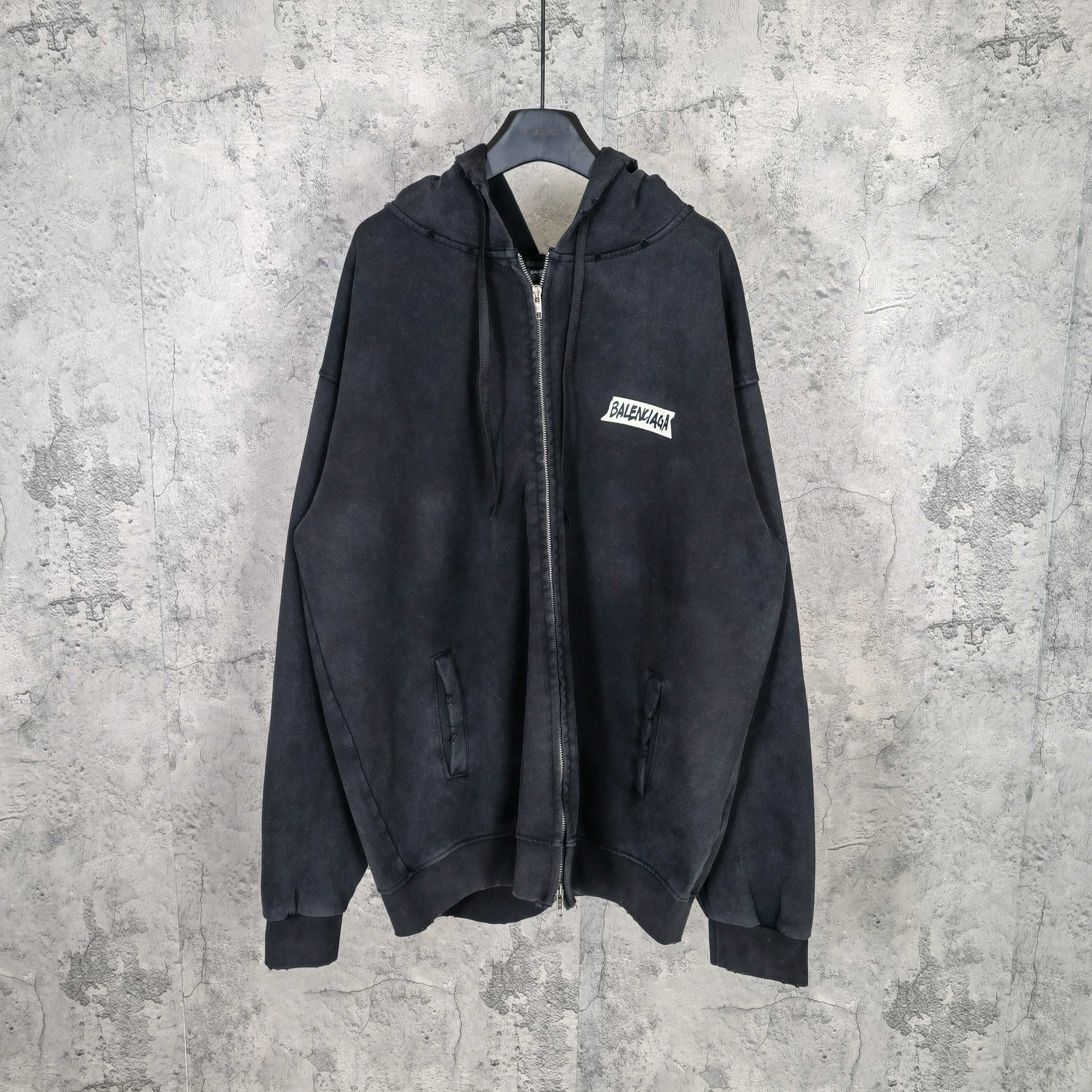 Black zip-up hoodie jacket with hood and chest logo patch