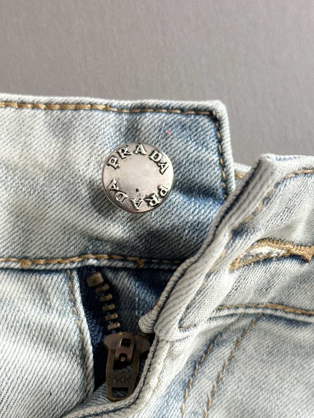 PRADA logo patch at denim waistband with button and zipper closure