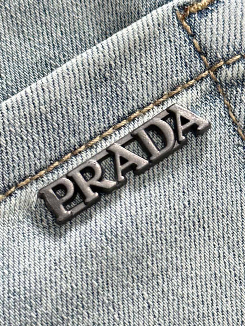 PRADA metal logo on light blue denim with golden contrast stitching