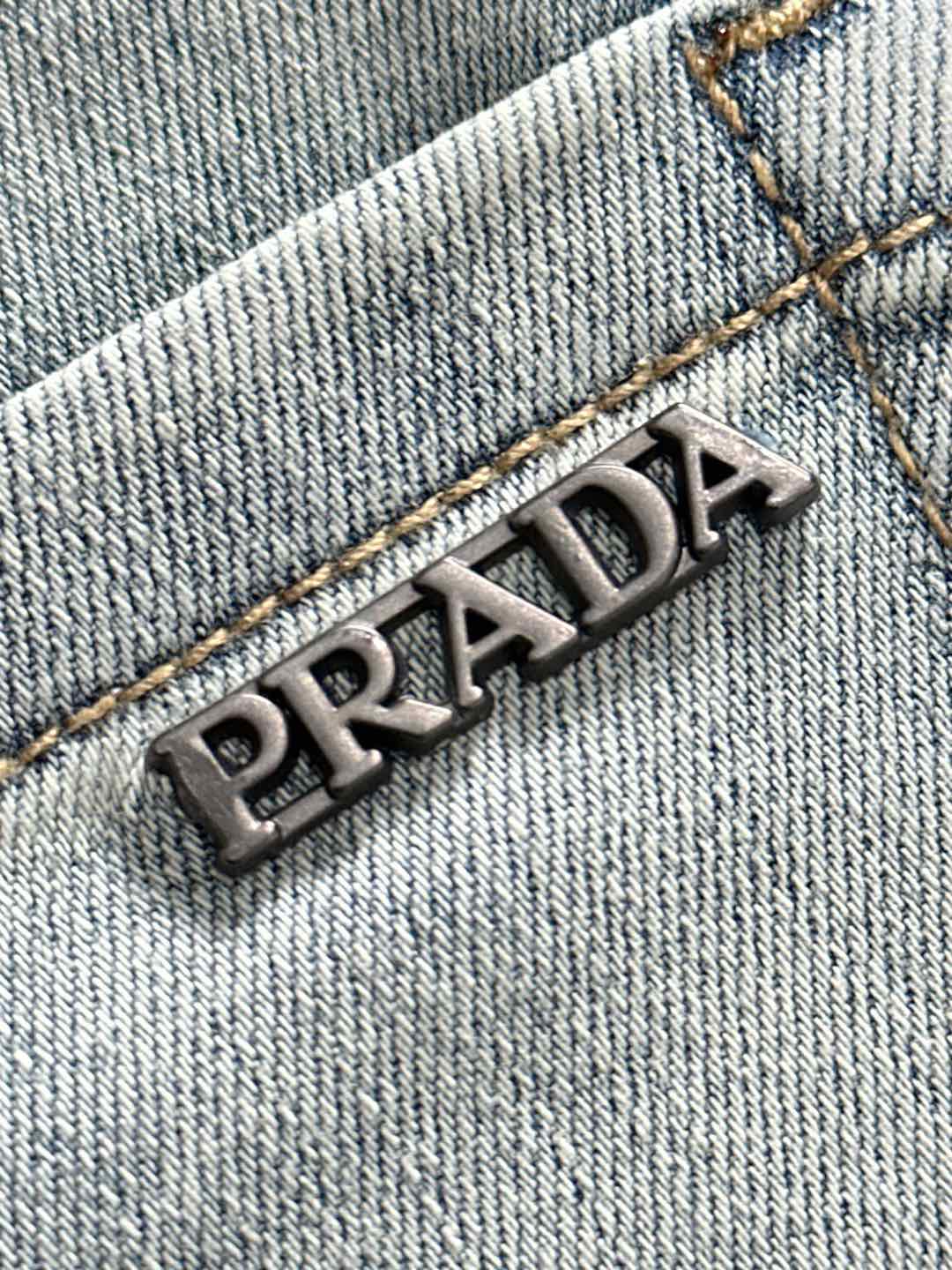 PRADA metal logo on light blue denim with golden contrast stitching