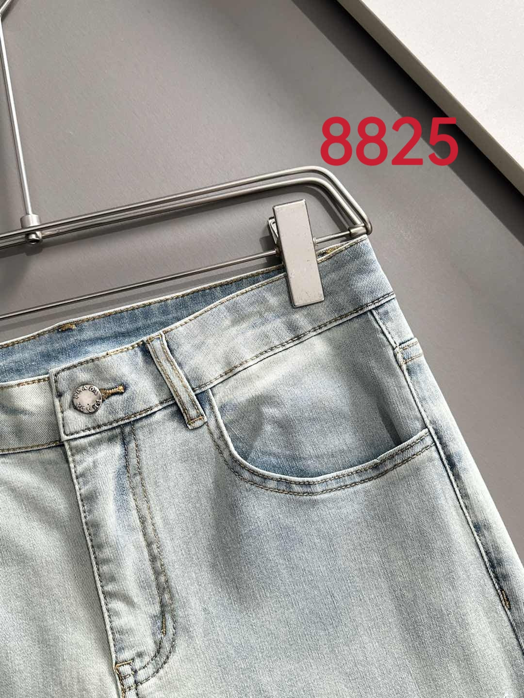 Light-wash denim pants front view with coin pocket and button closure