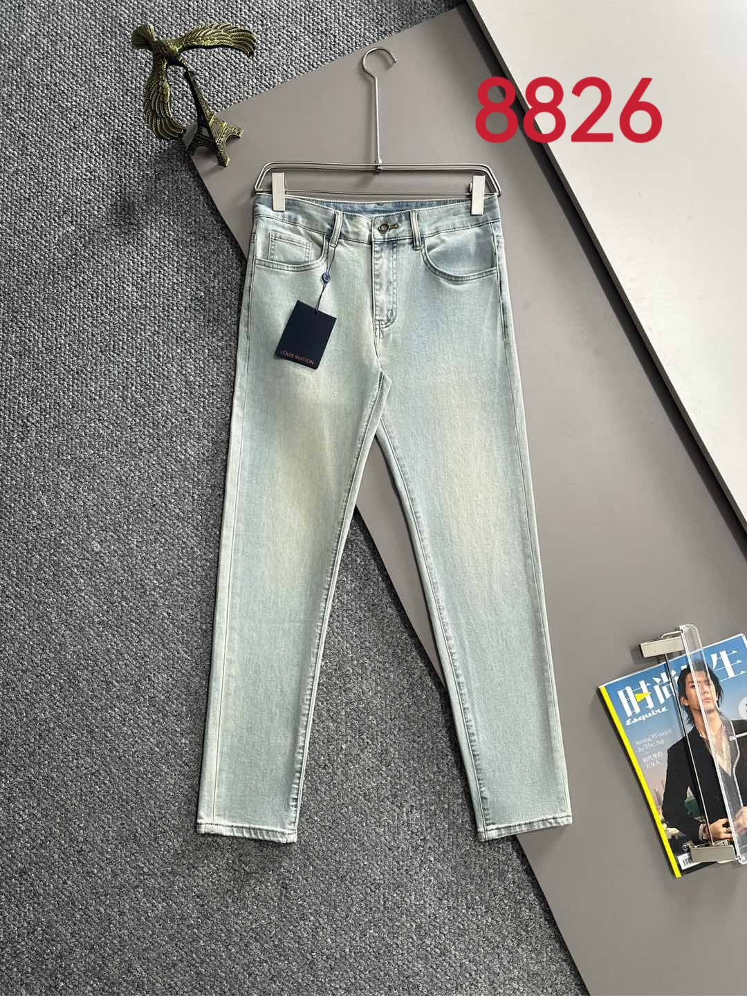 Light wash denim pants with front pockets, belt loops, and attached hanging tag