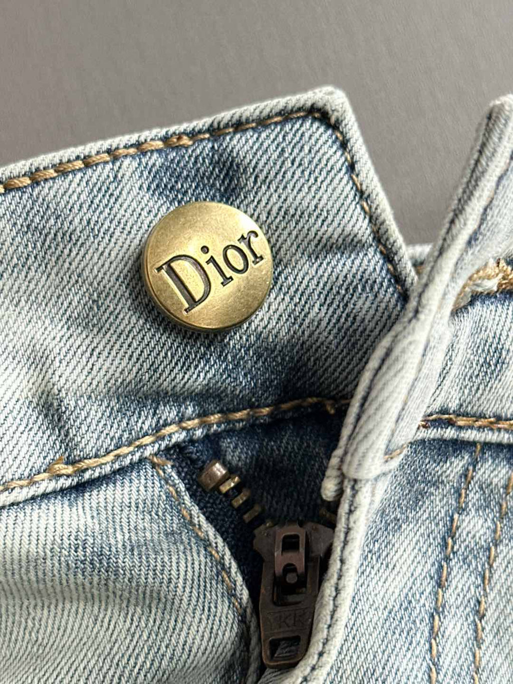 Light blue denim jeans front with gold Dior button and zipper area