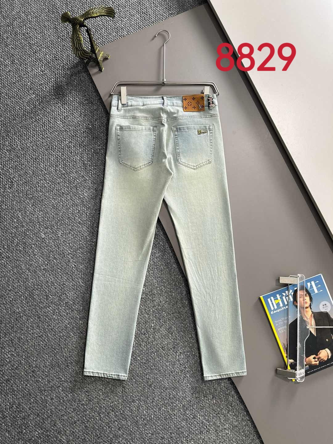 Light-wash denim jeans with stitched pockets and waistband, hanging on a hanger