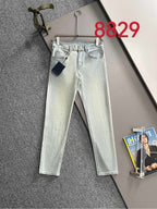 Light-wash denim jeans with front pockets and visible designer button, hung on a hanger