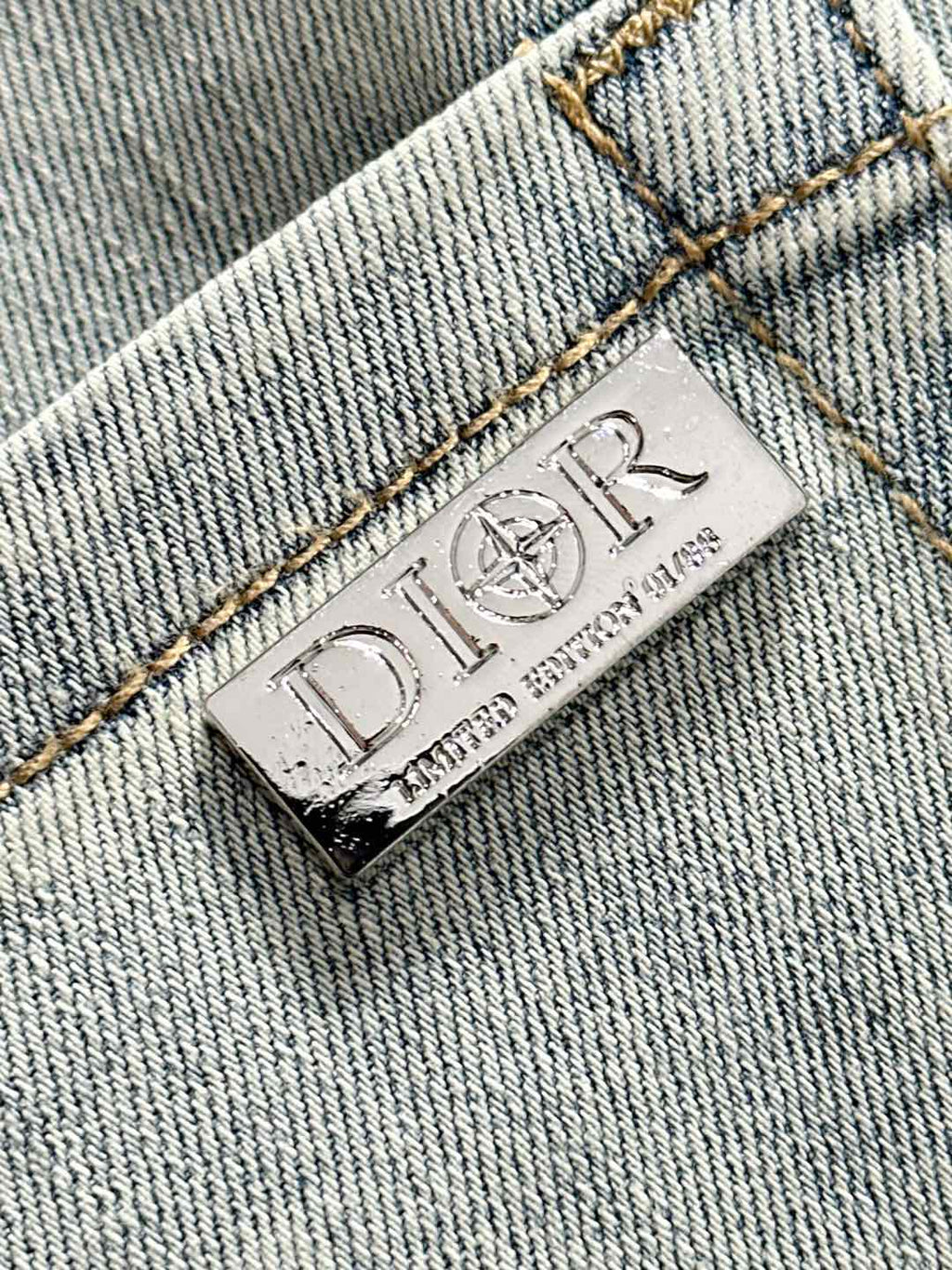 Dior leather brand label on light-wash denim, stitched hem and seams