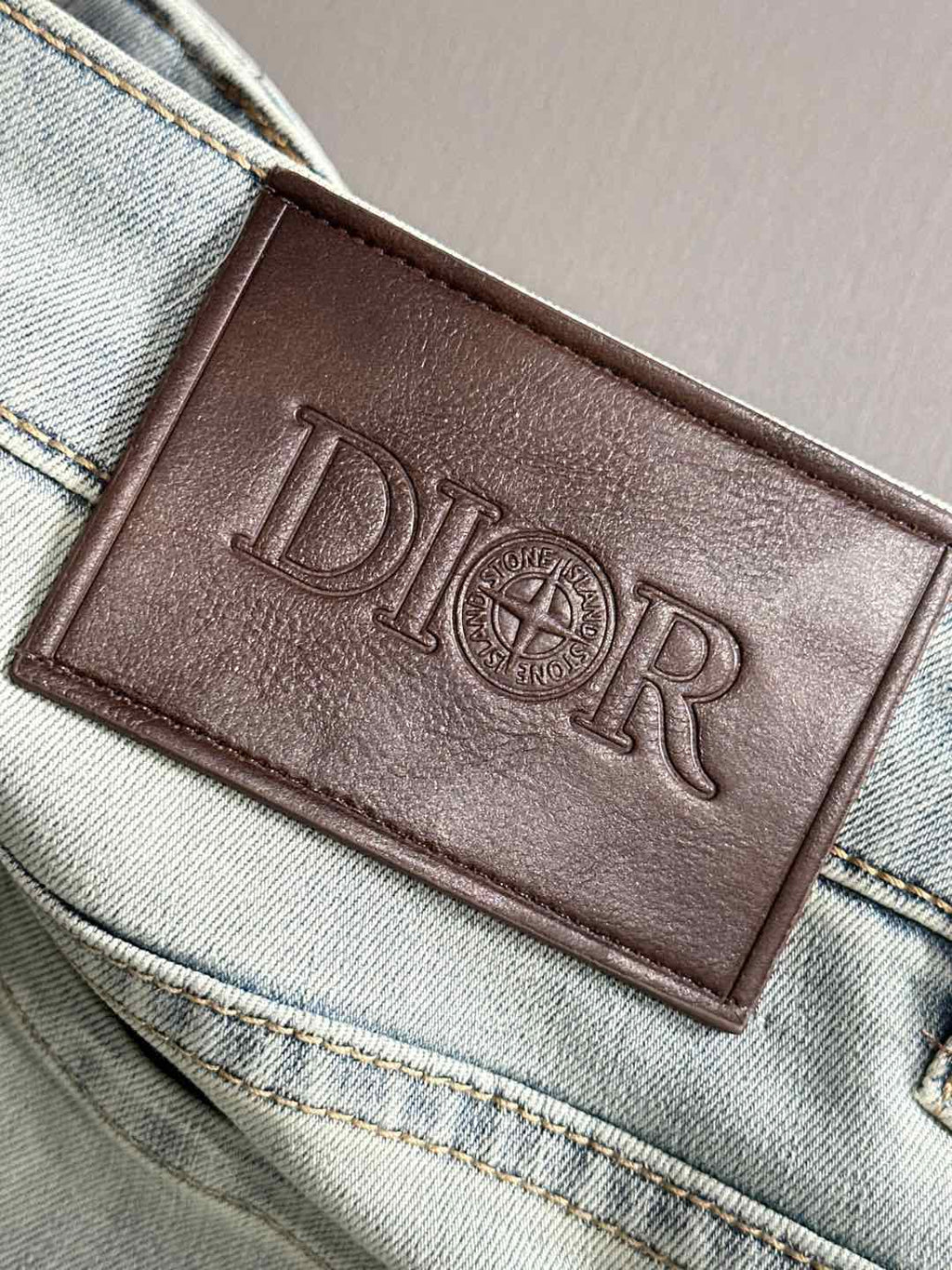 Dior leather logo patch on waistband of light-wash denim pants