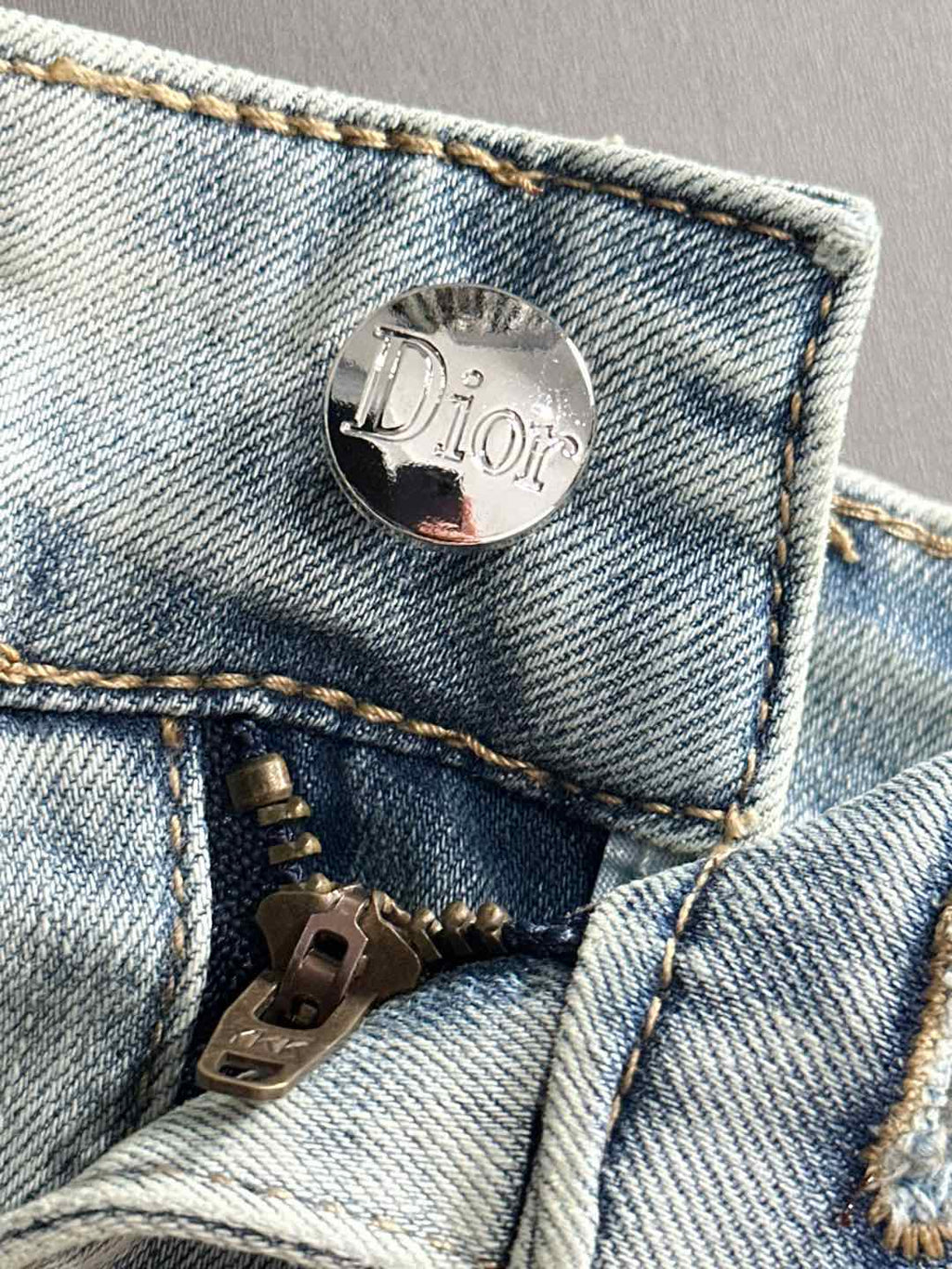 Dior jeans button and zipper close-up on light-wash denim pocket