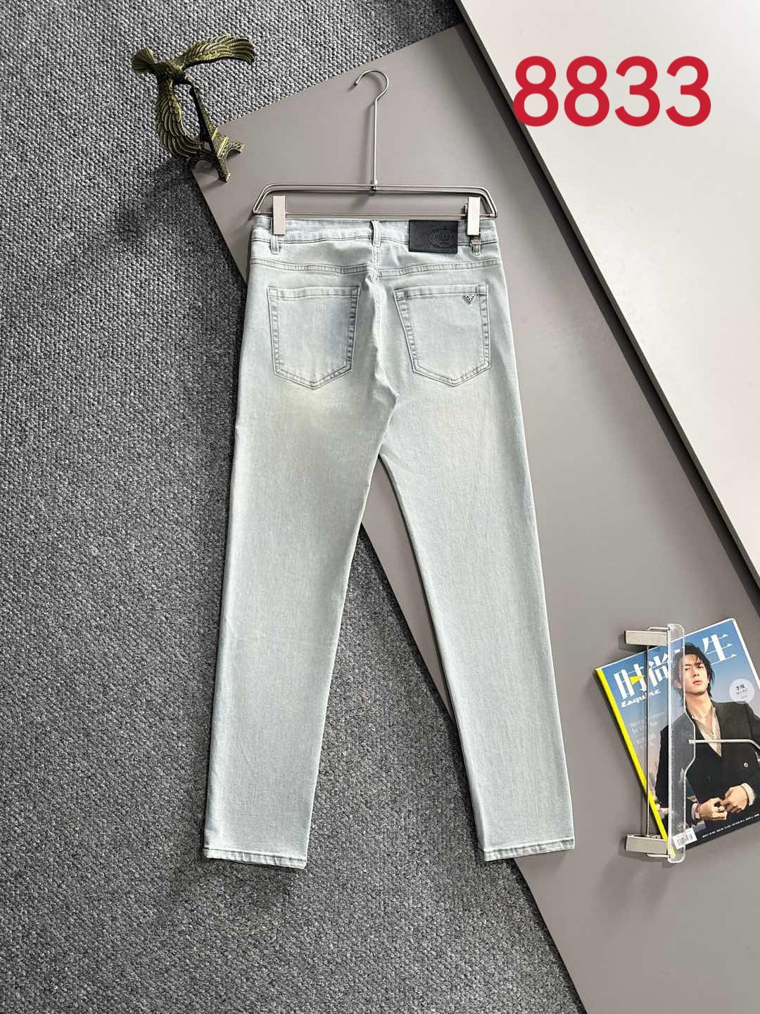 Light blue denim pants on hangers, five-pocket design and belt loops