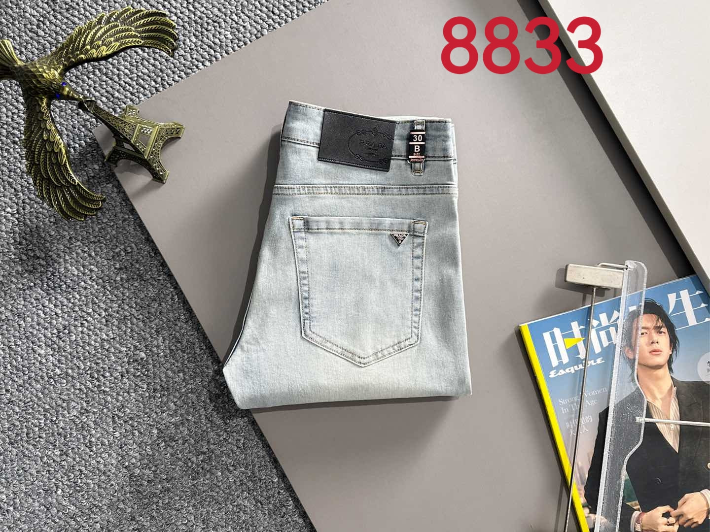 Light blue denim pants folded flat with front pockets and waistband logo patch