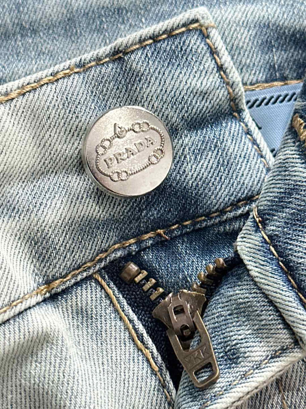 Prada logo metal button on light-wash denim front