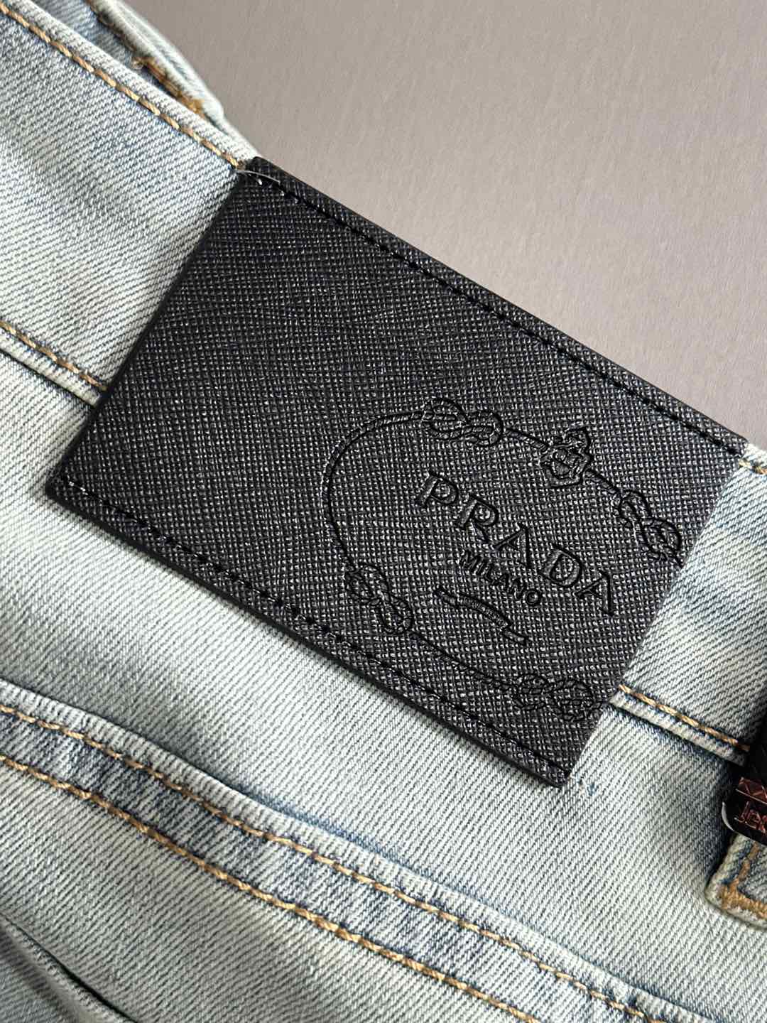 Prada logo leather label on light-wash denim pocket edge
