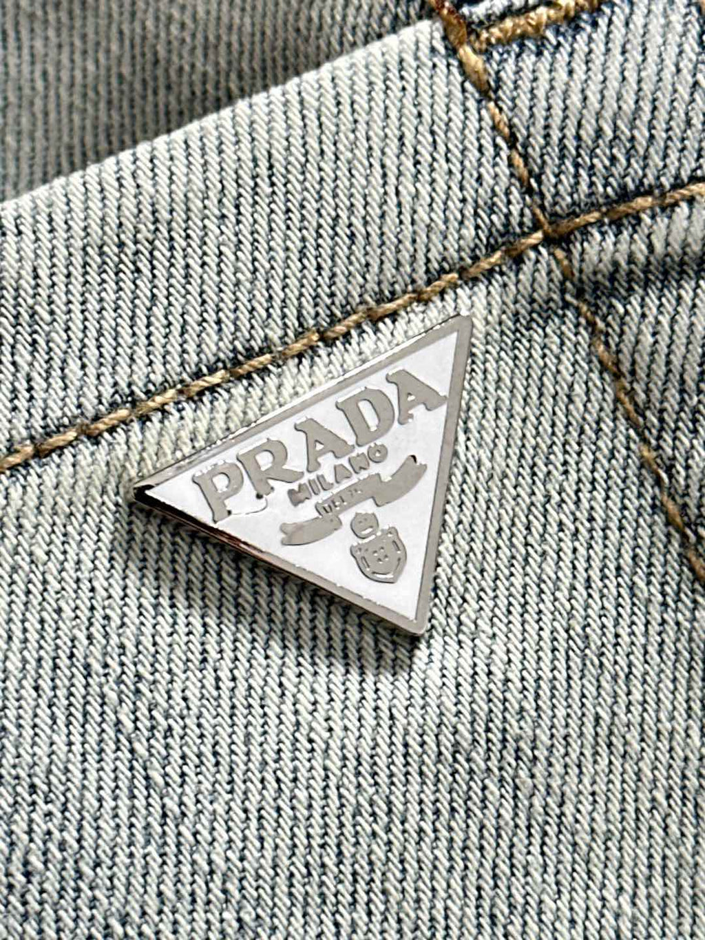 Prada triangular logo patch on light-wash denim coin pocket area