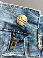 Dior gold button on light blue denim pocket with visible stitching