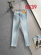 Light blue denim jeans with two front pockets and belt loops on a hanger.