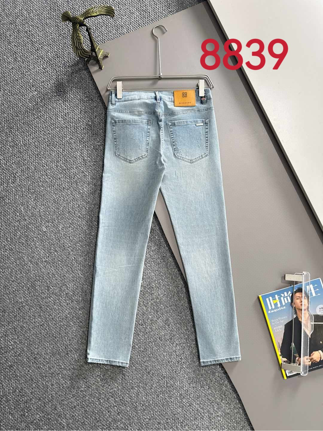 Light blue denim jeans with two front pockets and belt loops on a hanger.