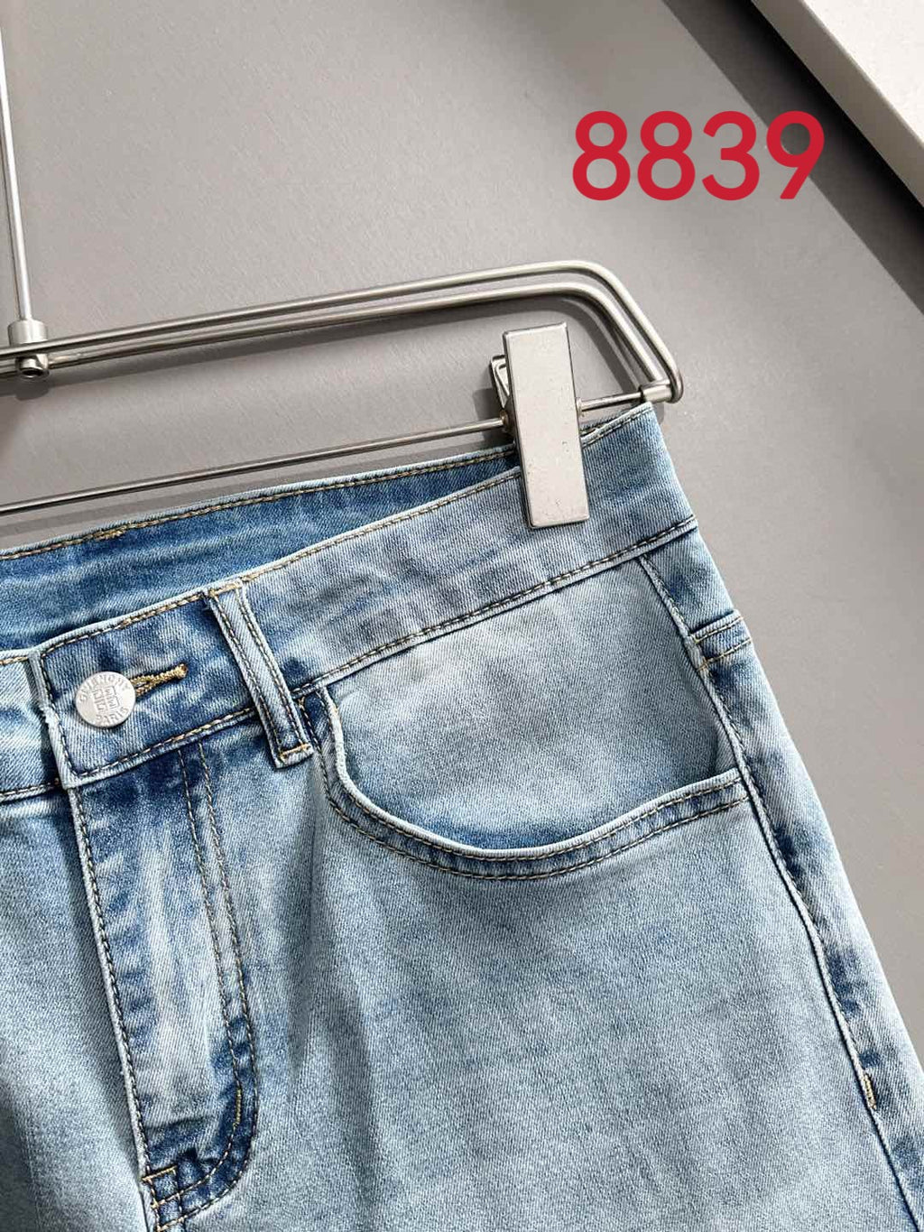 Close-up of light blue denim waistband and front pocket seam detail.