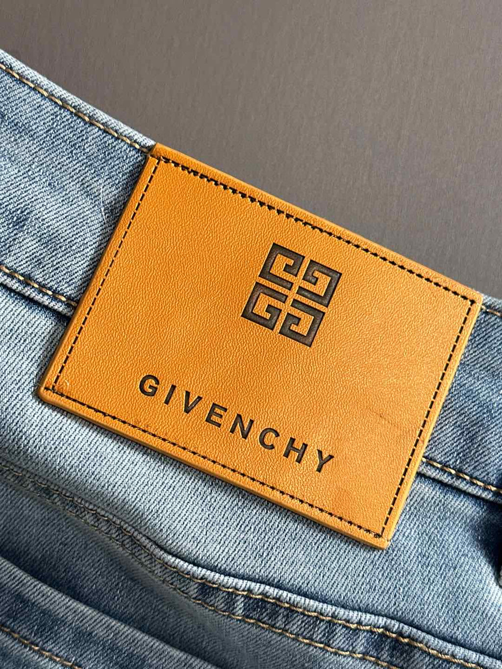 Orange GIVENCHY leather patch with logo on light blue denim.