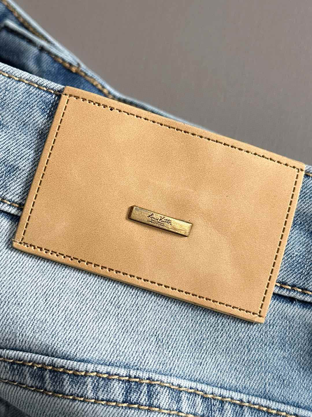 Louis Vuitton tan leather logo patch on light blue denim