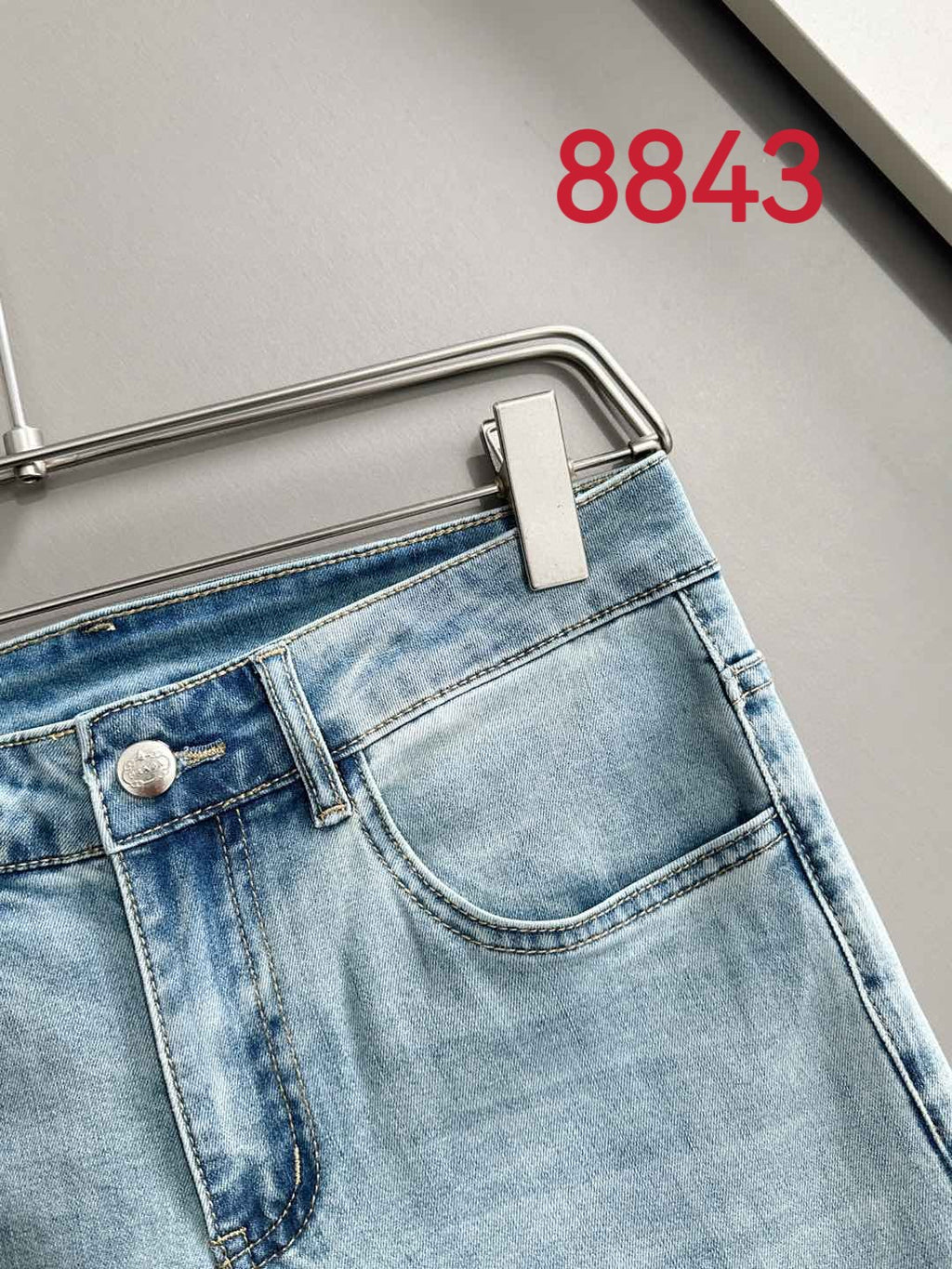 Light blue denim pants with front button closure and metal logo hardware.
