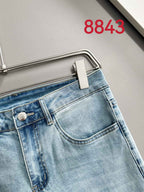 Light blue denim pants with front button closure and metal logo hardware.