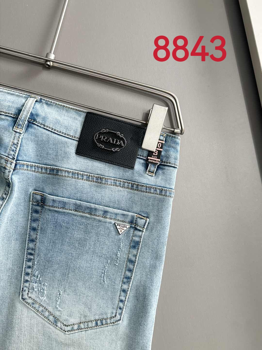 Light blue denim waistband with Prada leather patch and belt loops.
