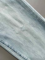 Light blue denim fabric detail with small stitched marks near the seam.