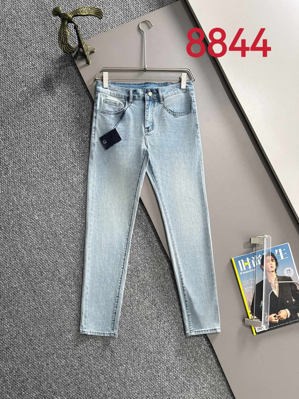 Light blue denim pants on hanger with belt loops and front pockets