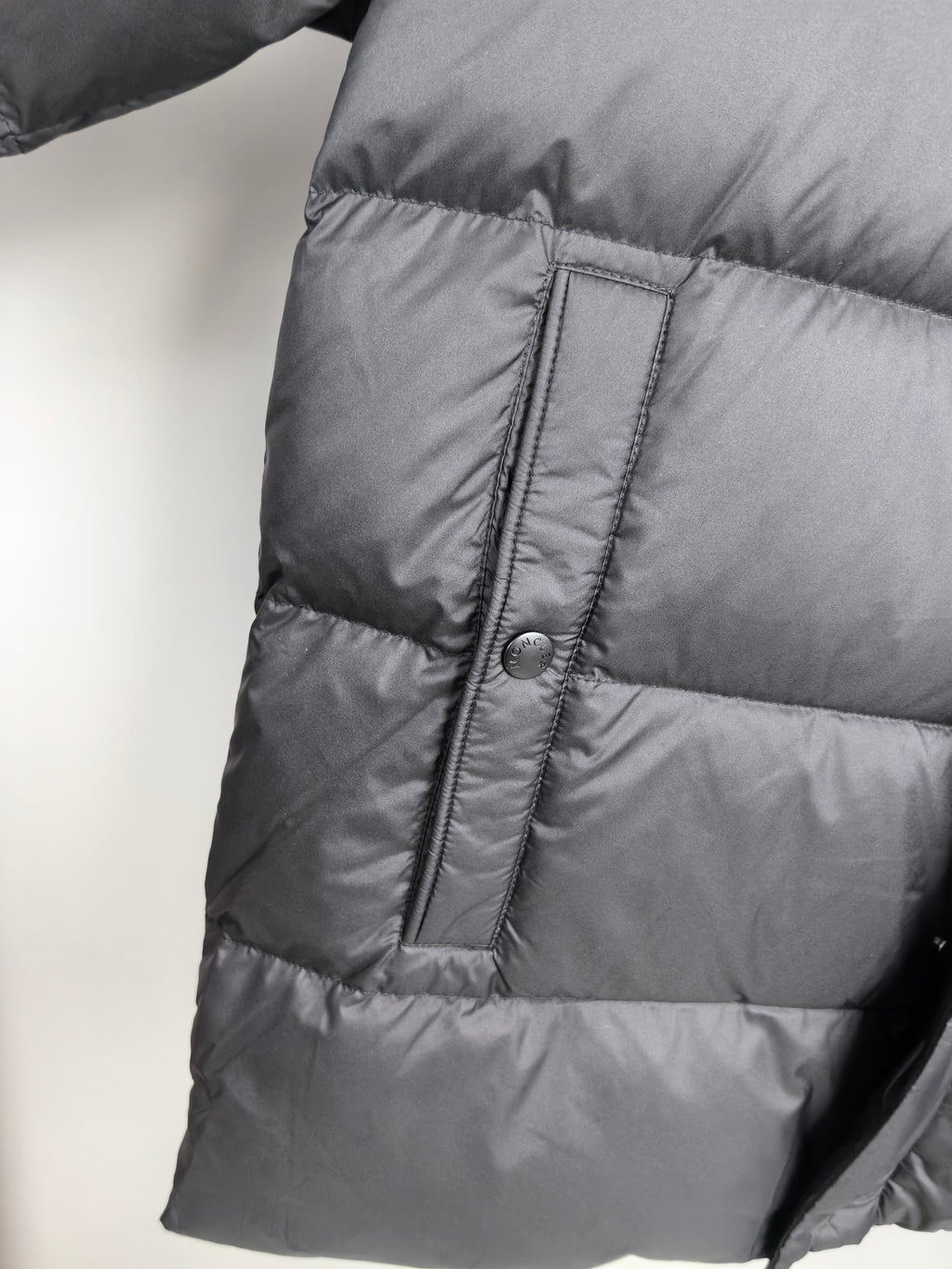 Long Moncler puffer jacket side panel with stitched seam and button placket