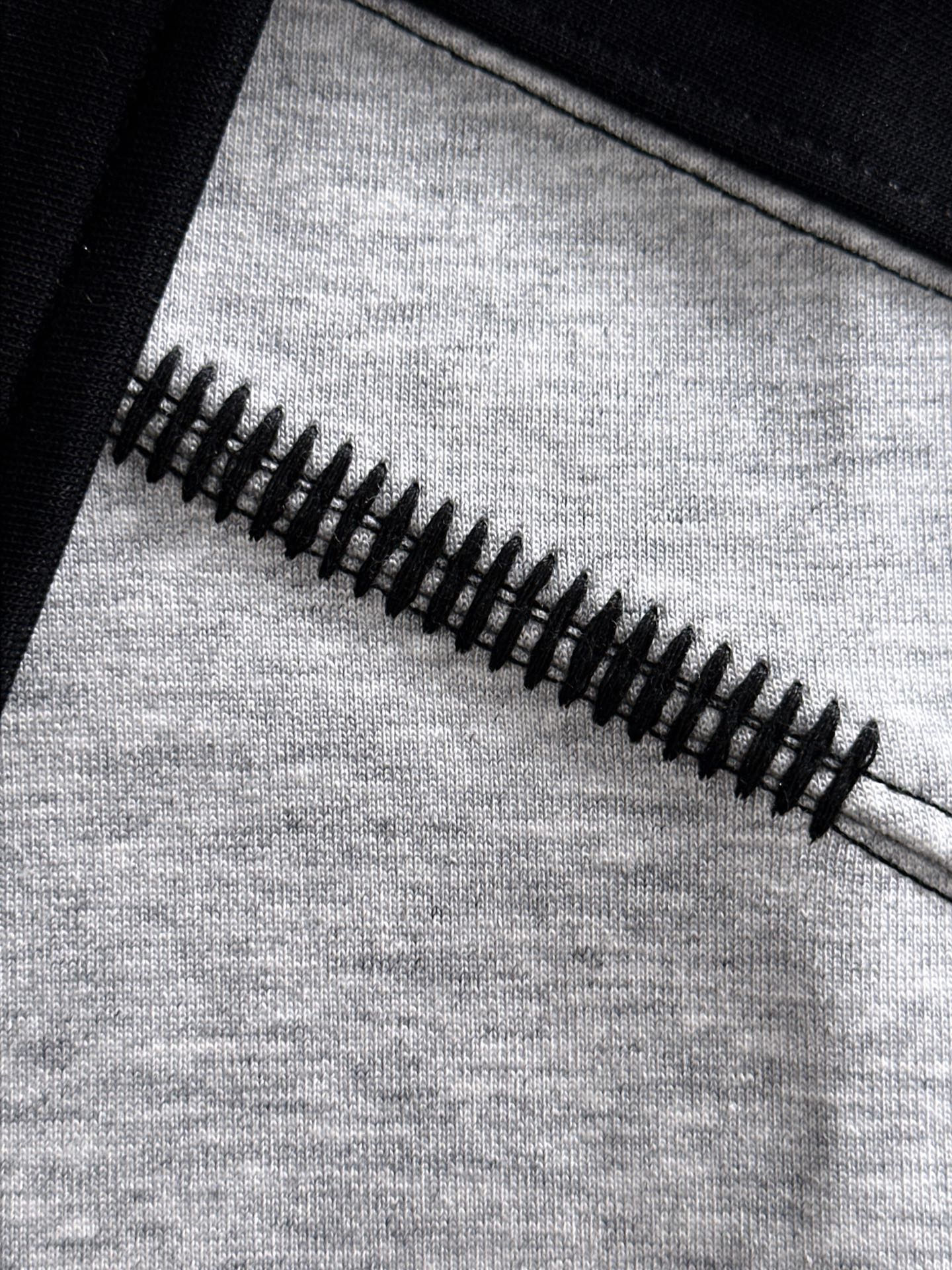 Long-sleeve shirt zipper detail on grey fabric with black trim