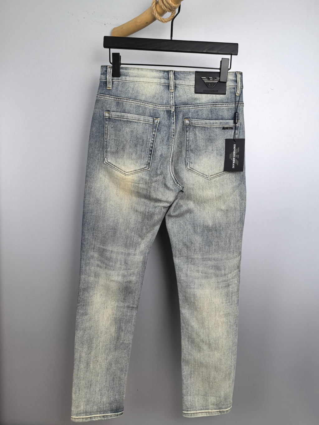 Light wash denim jeans on a hanger, classic five-pocket design and belt loops