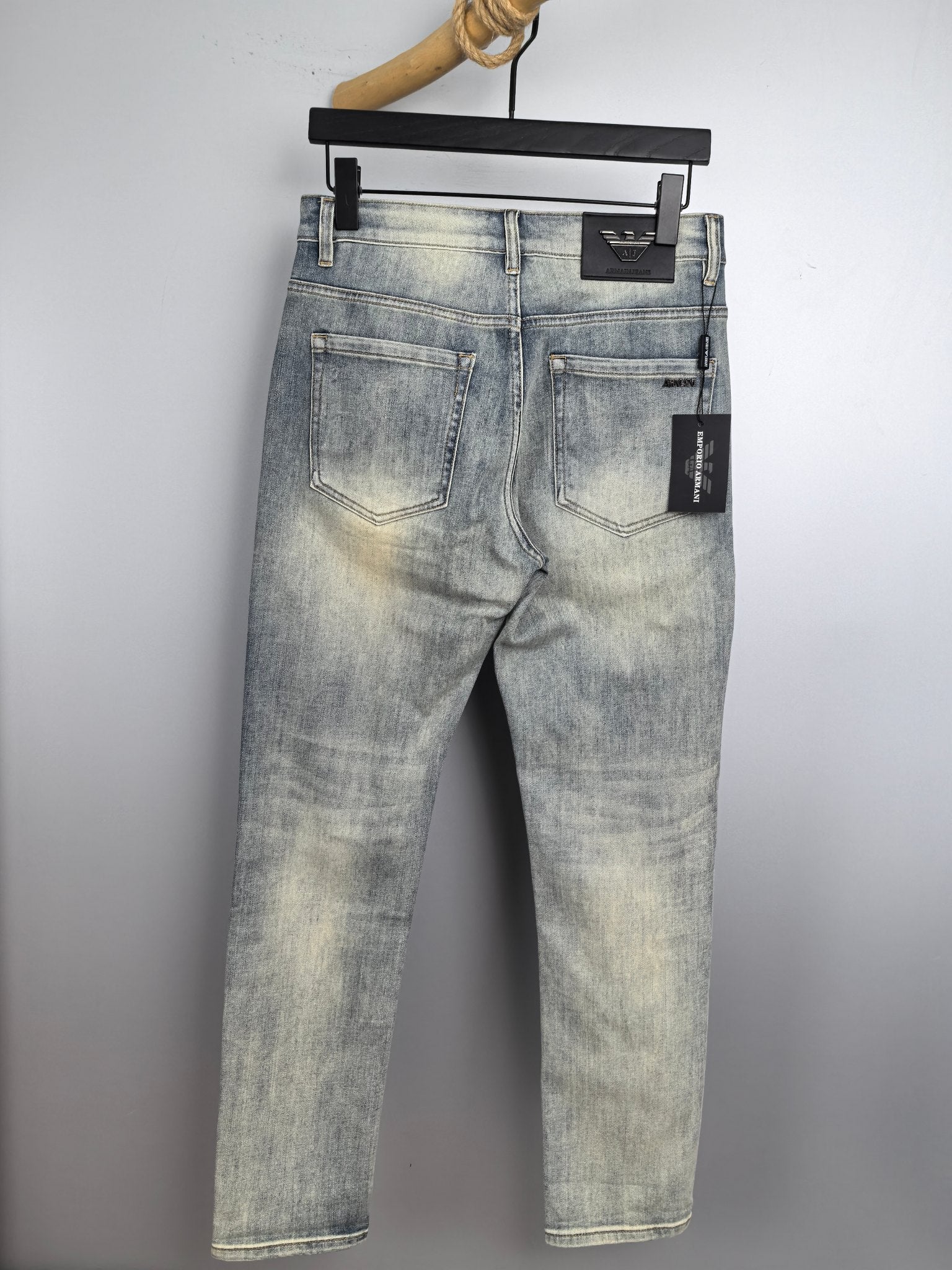 Light wash denim jeans on a hanger, classic five-pocket design and belt loops