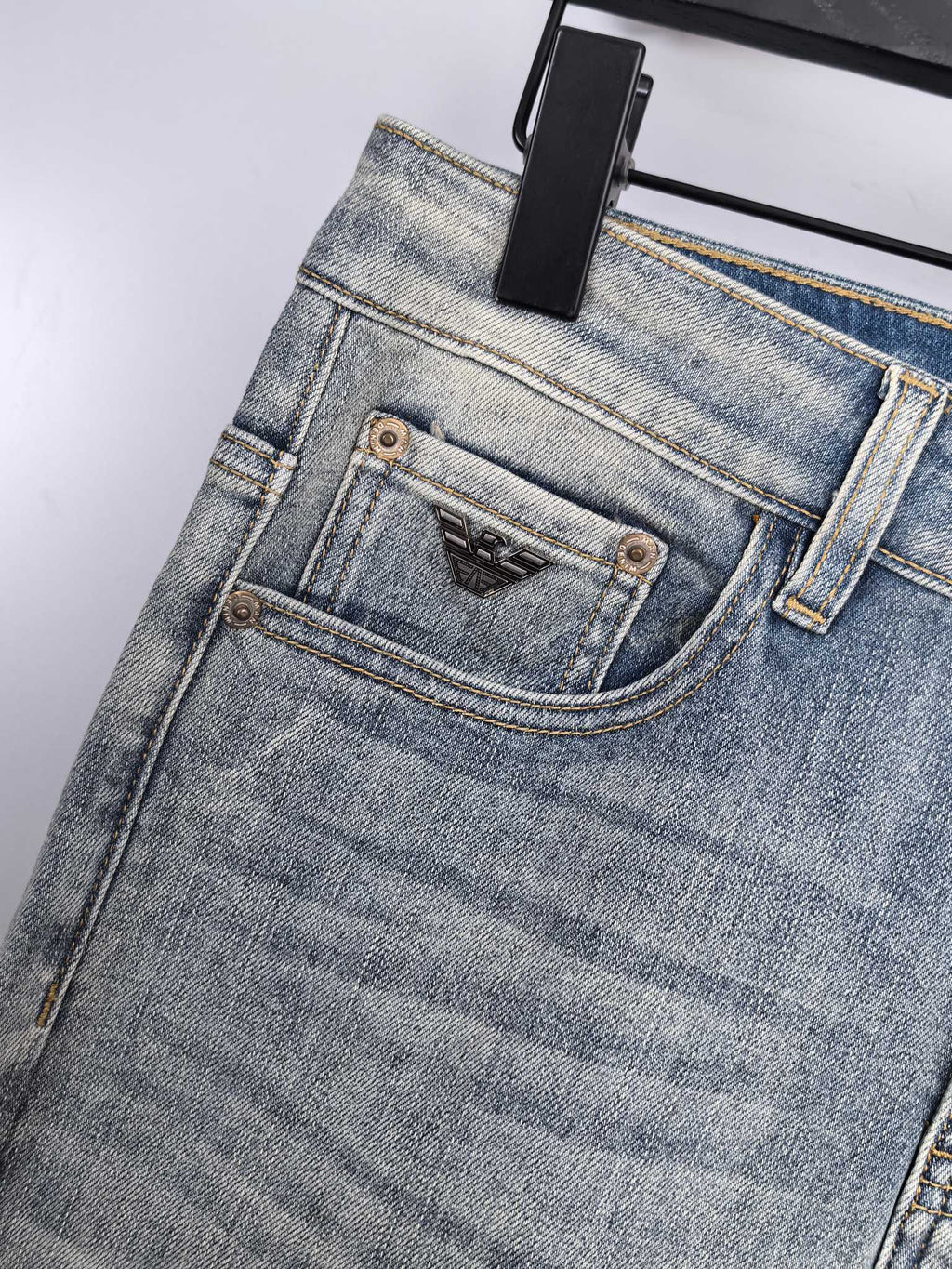 Light wash denim jeans close-up of waistband and front button with brand patch