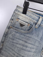 Light wash denim jeans close-up of waistband and front button with brand patch
