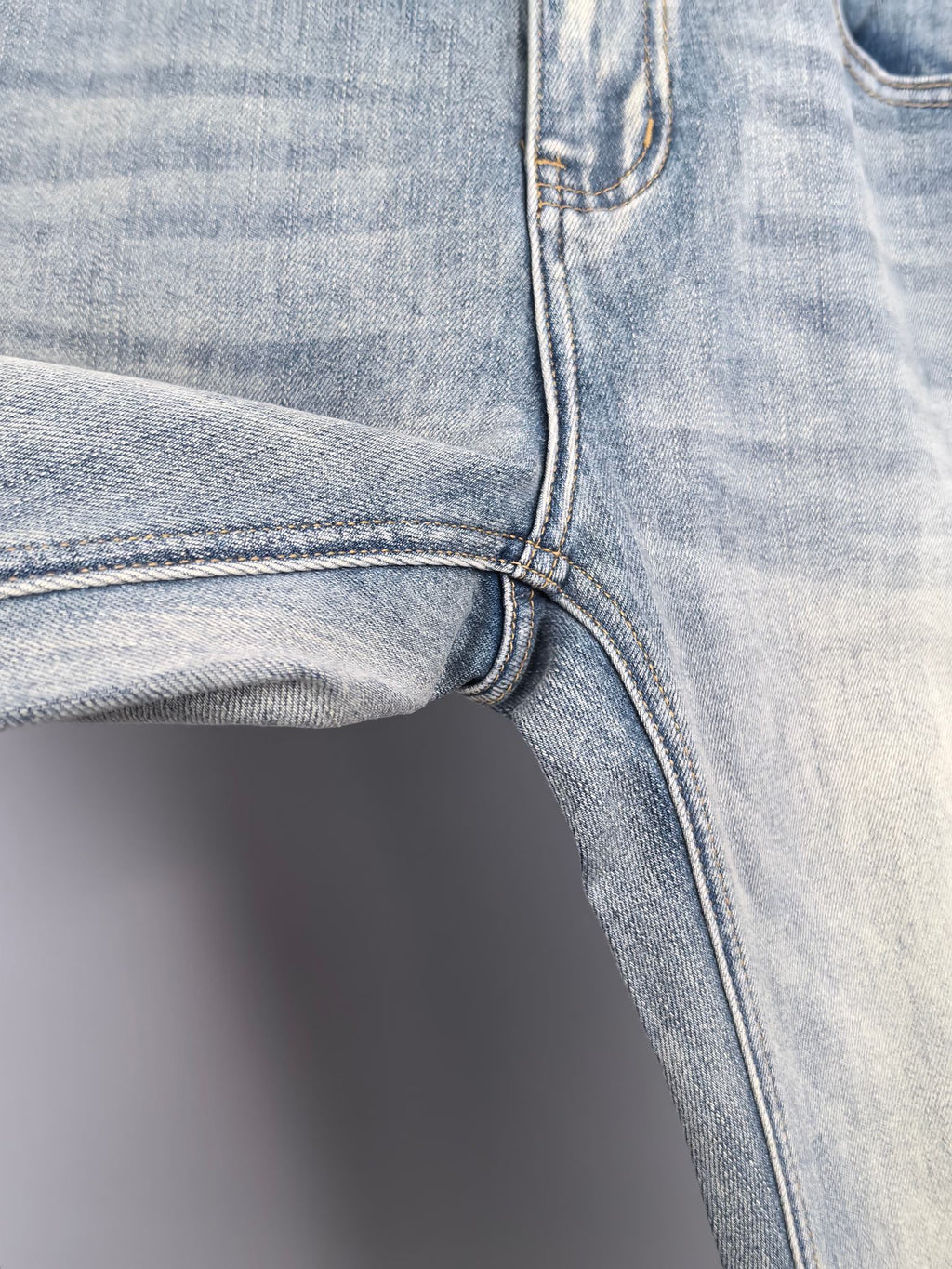 Denim jeans front knee and inner seam with curved stitching and hem edge