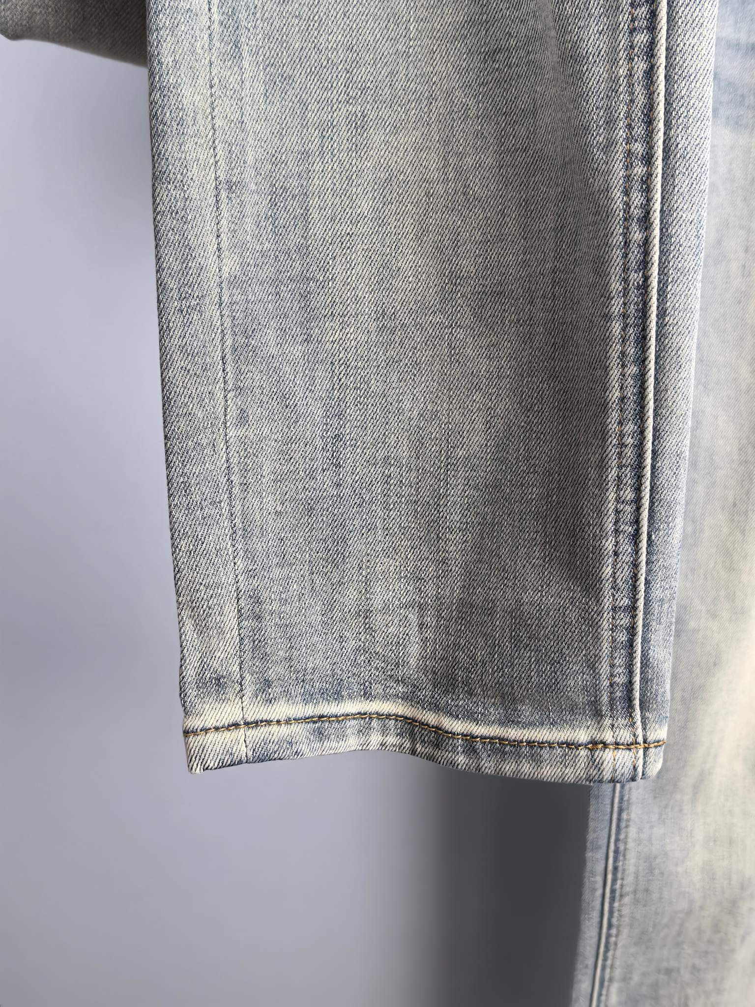 Light wash denim jeans hem with visible stitching at the bottom cuff