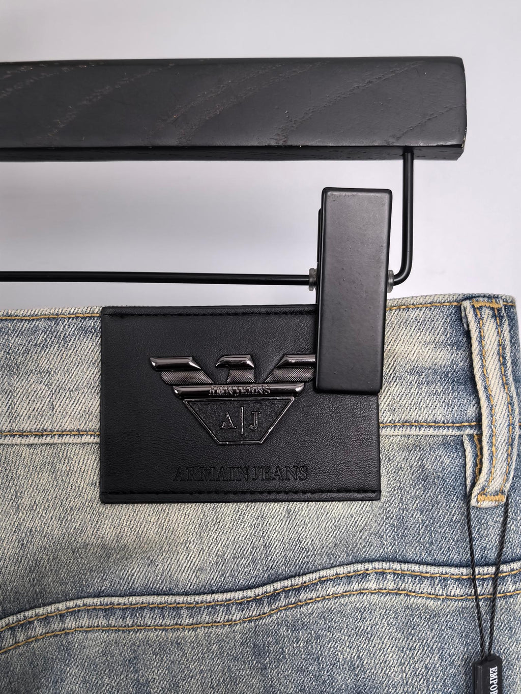 Back waistband and leather logo patch on light wash denim jeans with hang tag