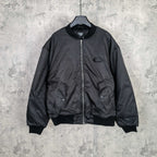 Dark bomber jacket with front zip and ribbed cuffs, oval logo patch at chest