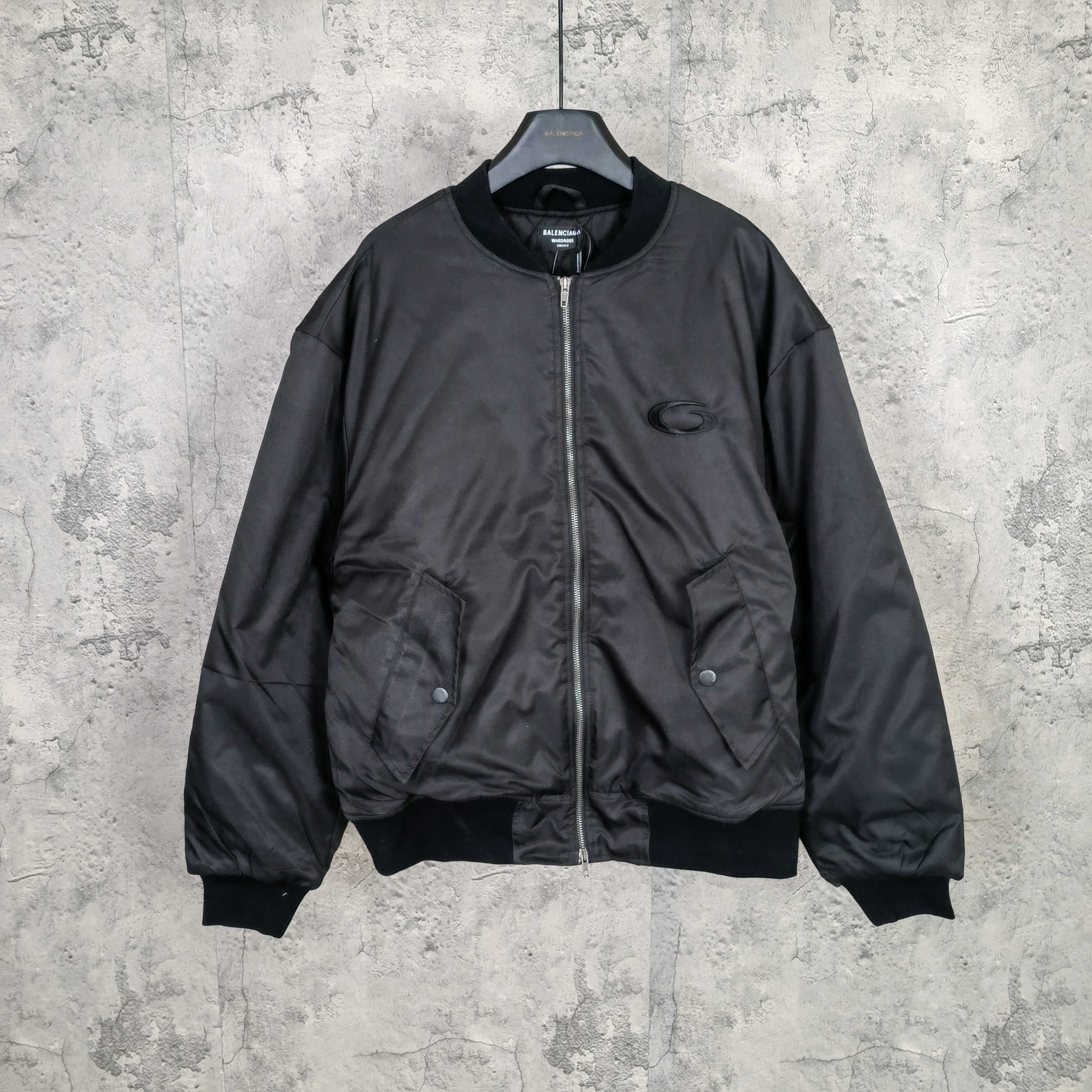 Dark bomber jacket with front zip and ribbed cuffs, oval logo patch at chest