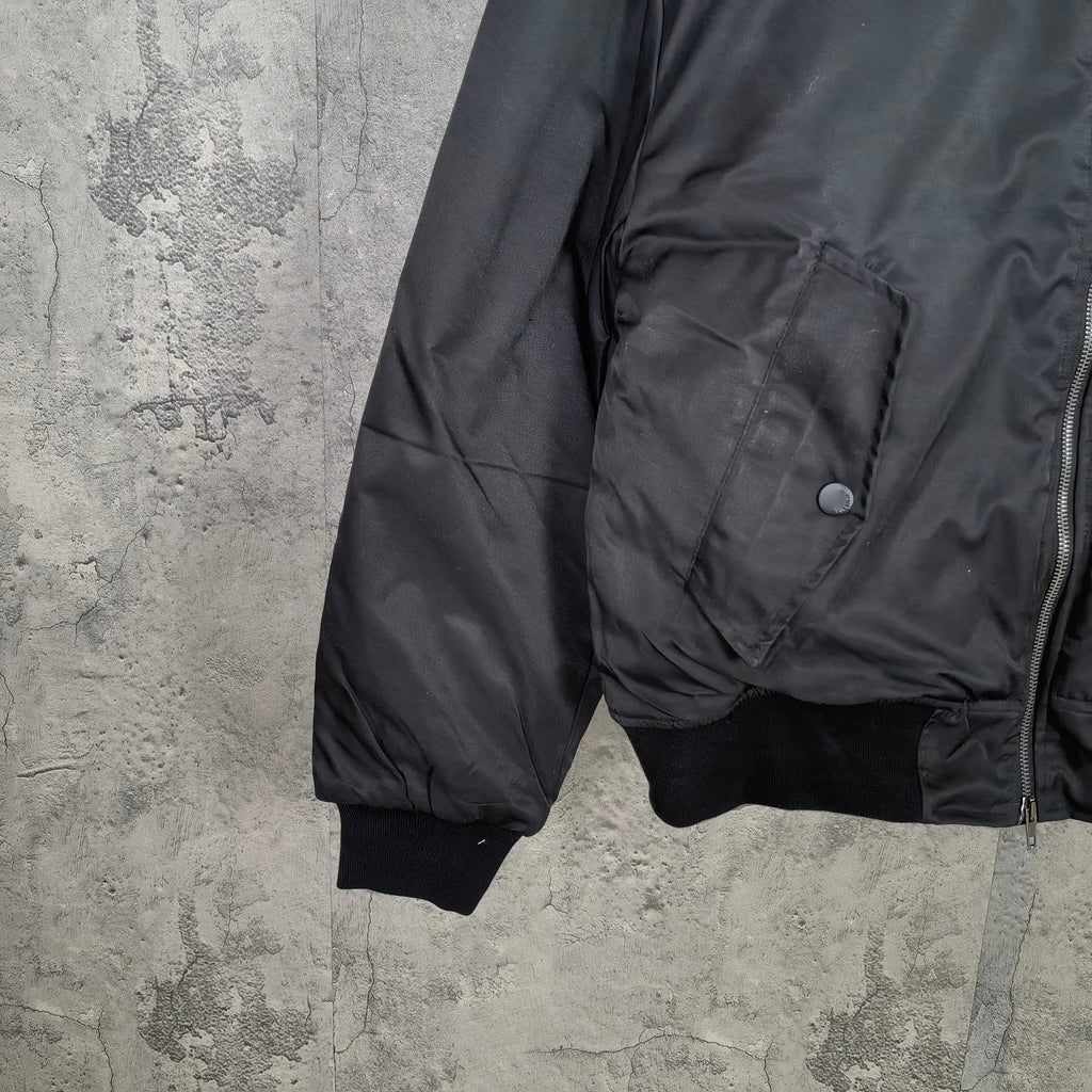 Dark bomber jacket with flap pocket, ribbed cuffs, and zippered front edge