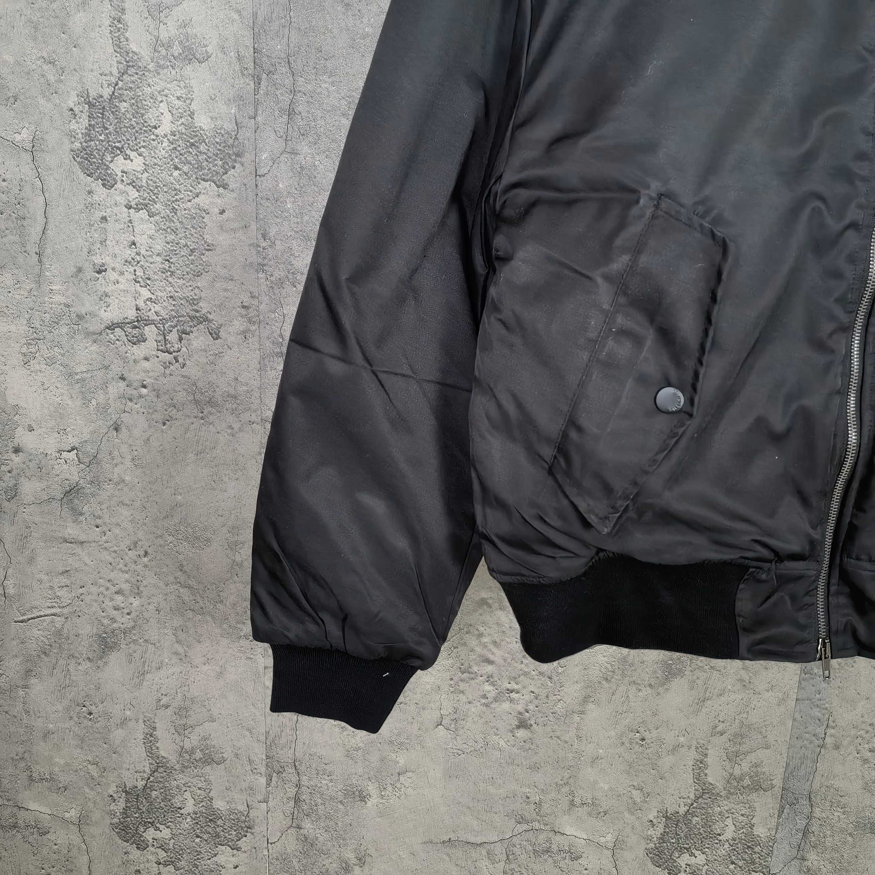 Dark bomber jacket with flap pocket, ribbed cuffs, and zippered front edge