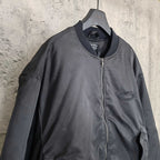 Dark bomber jacket with front zip and oval logo patch at chest