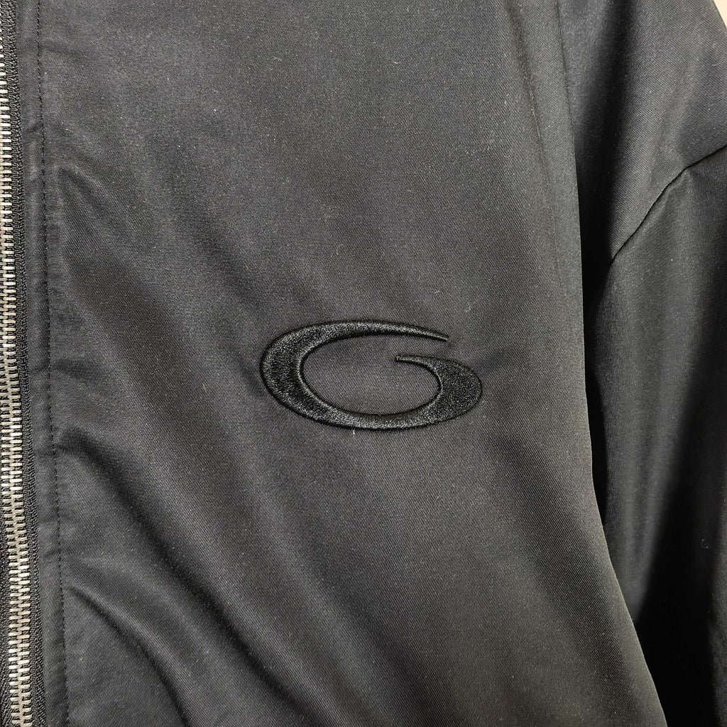 Oval embroidered logo patch on dark bomber jacket sleeve