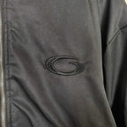 Oval embroidered logo patch on dark bomber jacket sleeve